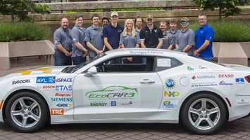 The car that competed in the EcoCAR 3 Challenge in Year 3 and the team standing behind it
